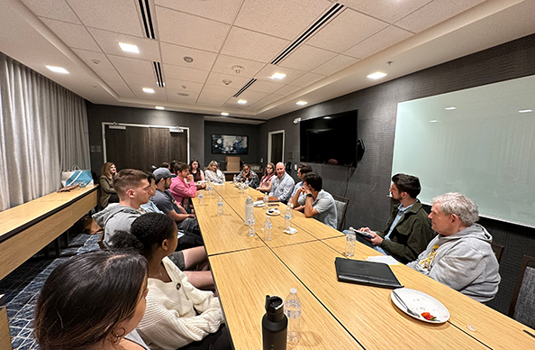 LSU students surrounding the table at a welcome dinner.