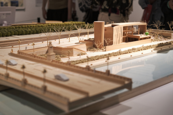 Image of an architectural model of a commercial building and surrounding greenscape and infrastructure.