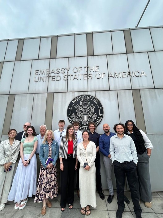 group of people posing in front of an embassy