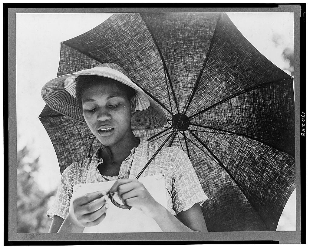 Historical black and white photograph of a woman holding an umbrella