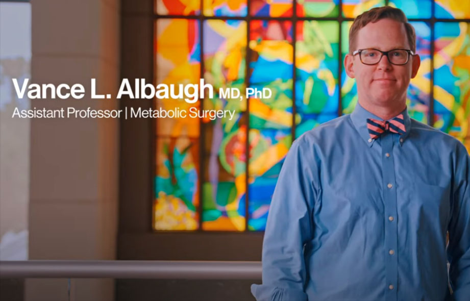 Dr. Vance L. Albaugh and Dr. Amelia Jernigan pose in front of a stained-glass window.